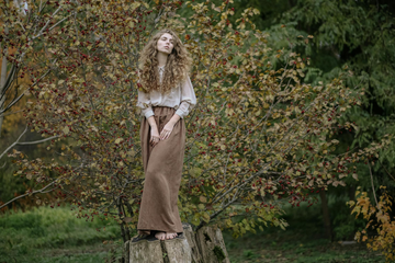 A model with thick, voluminous hair stood on a tree trunk for a shoot.