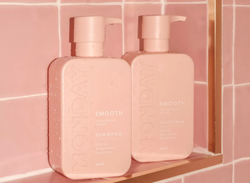 Two bottles of MONDAY Shampoo and Conditioner for fine, thin, and lifeless hair. The pink bottles have  a pump dispenser and is labeled with the product name and details, including being SLS free, paraben free, and cruelty free.