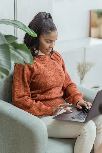 Alt text: Woman on a computer with her hair pushed into a tight ponytail. Taken from Pexels