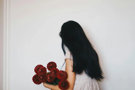 Girl with long black hair holding a bunch of flowers. Picture taken from Pexels
