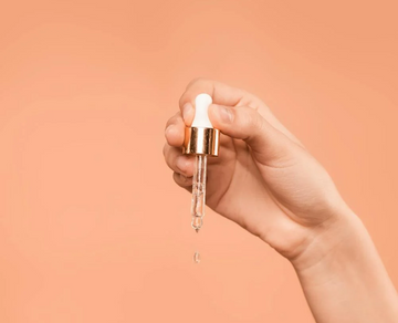 Image of a hand and a pipette of argan oil.