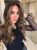 Woman in a black shirt with voluminous, wavy, long brown hair