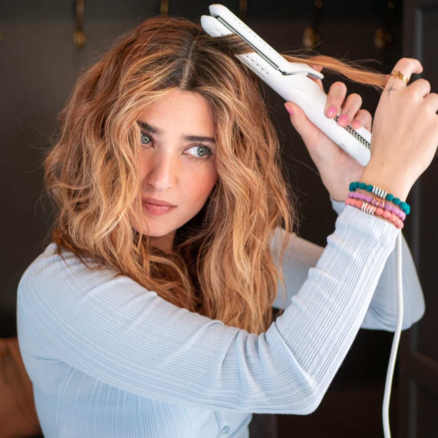 Red haired woman using the TYME Iron Air: Stardust to curl her hair.