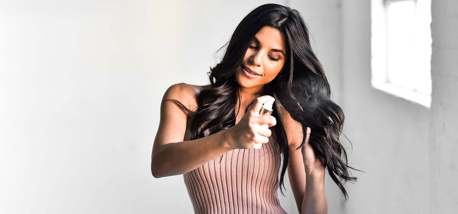 Woman with black hair and TYME curls spraying TYMELESS