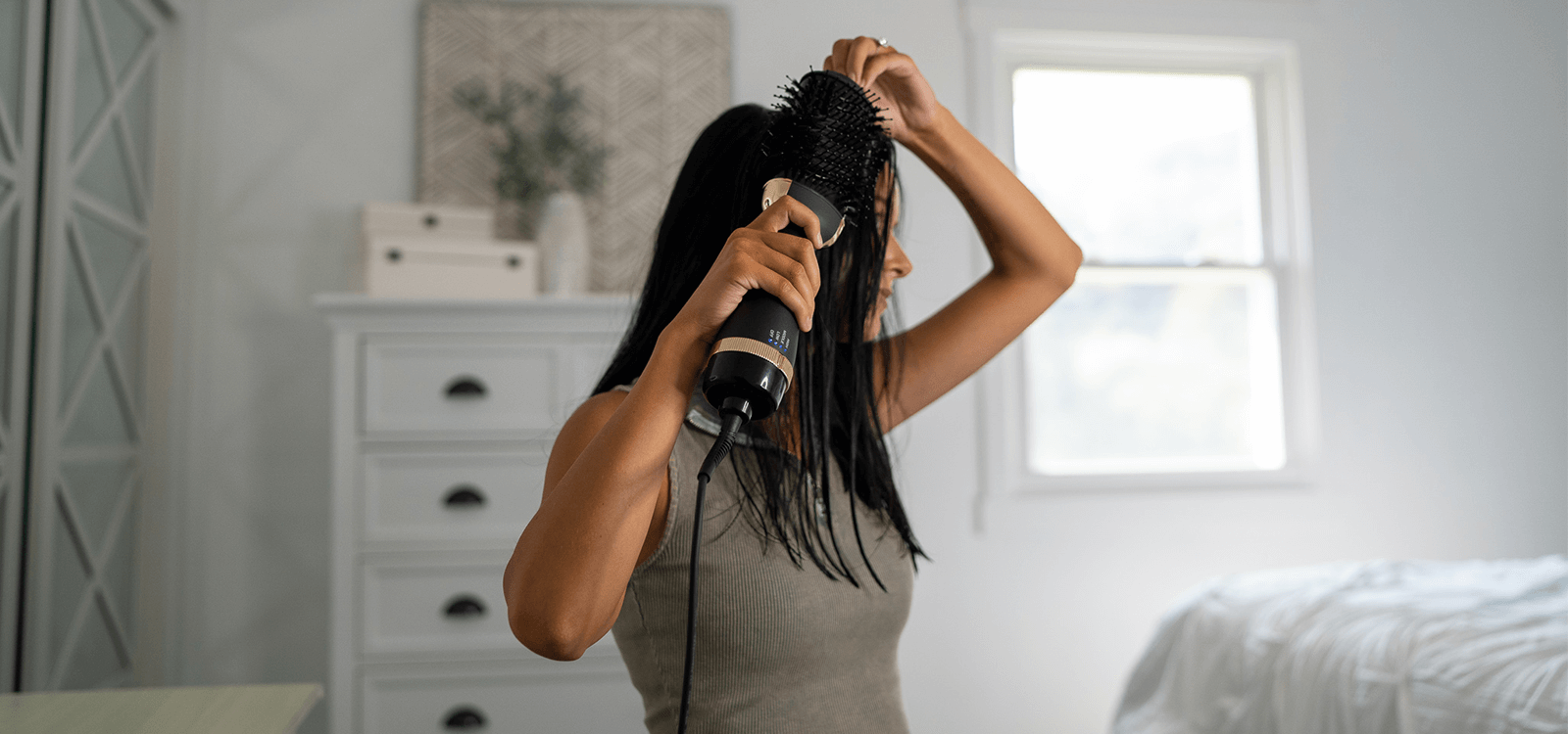 Woman with dark hair using the TYME BlowBrush to style her wet hair