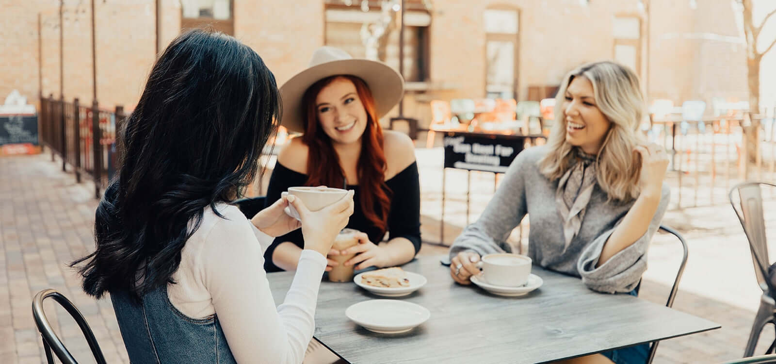 3 women sitting at table having coffee and laughing with TYME curls