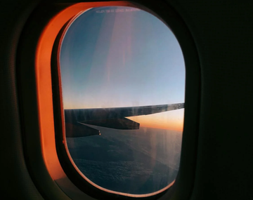 Image of an airplane window with a sunset.