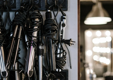 Image of lots of hot hair tools hanging up on the wall.