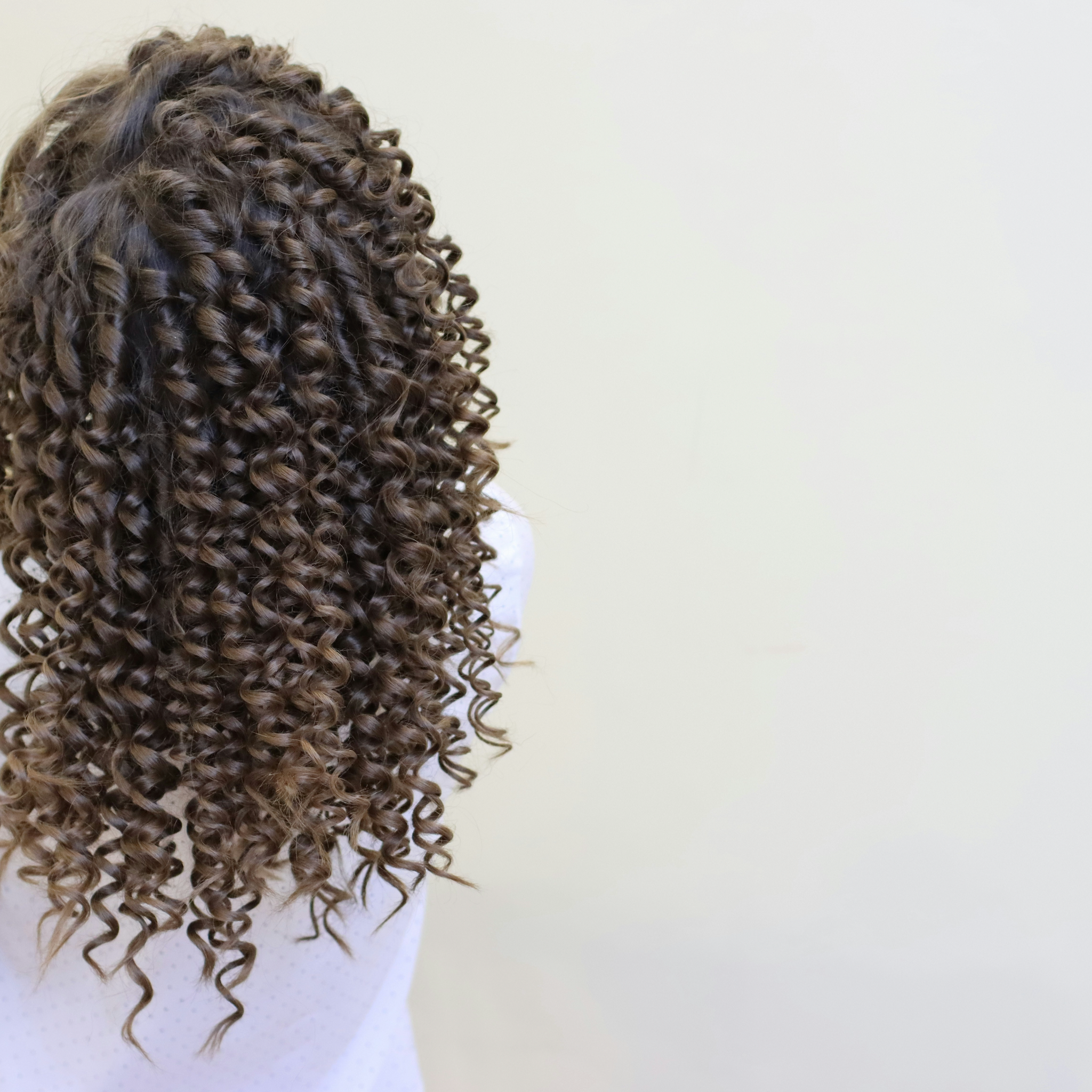 Woman with long curly hair walking down a city street.