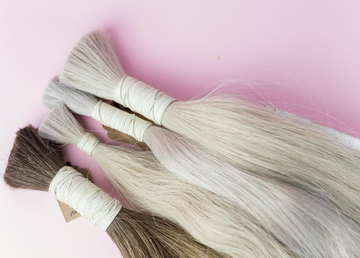 Image of dark blonde hair extensions on a pink surface