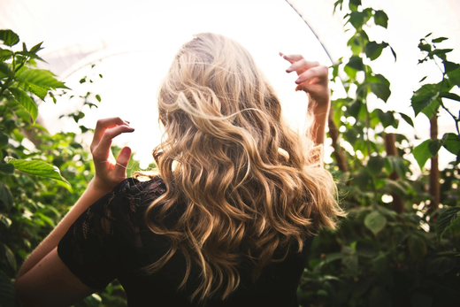 The back of a young woman with blonde, highlighted hair, swishing in the breeze.