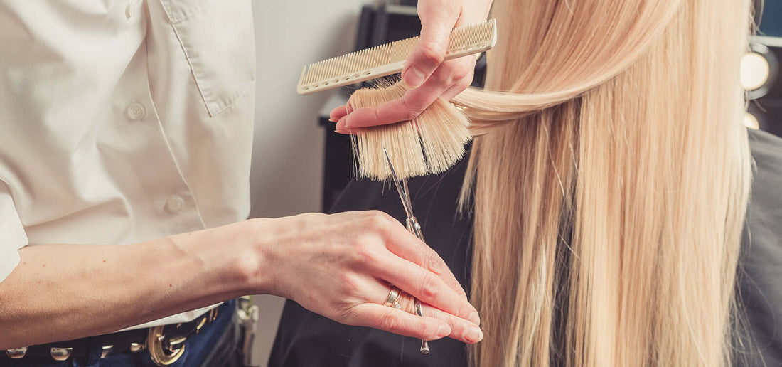 Woman getting blonde hair trimmed with scissors in picture