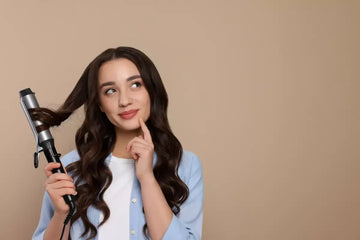 Beautiful woman using curling hair iron