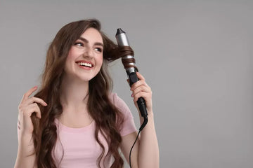 Young woman curling hair with iron