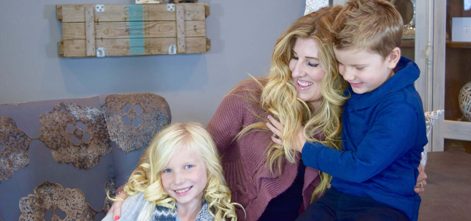 mother with blonde hair smiling and hugging her son and daughter