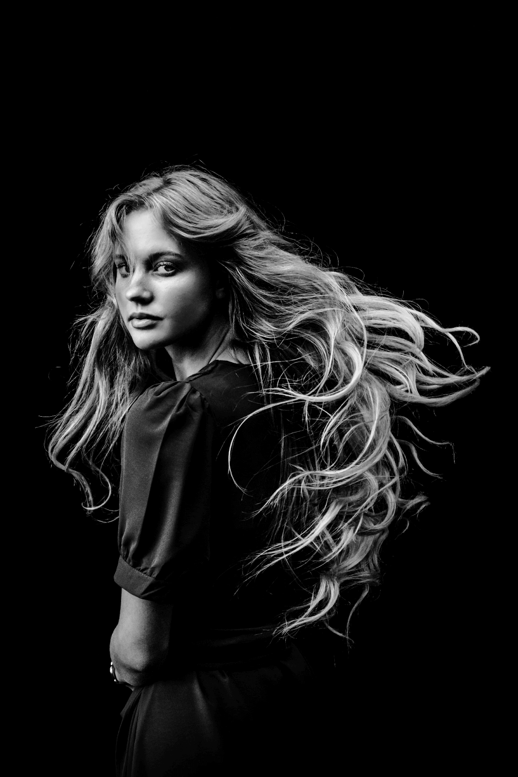 Girl with long blonde hair who is looking at the camera over her shoulder. Taken from Unsplash