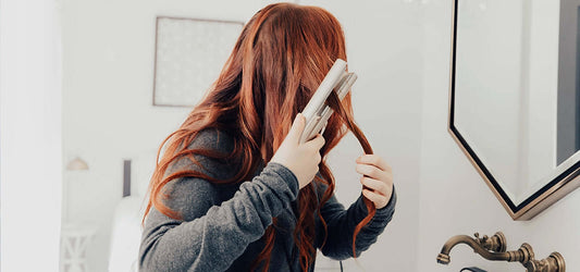 Woman with Red hair curling in mirror with TYME iron