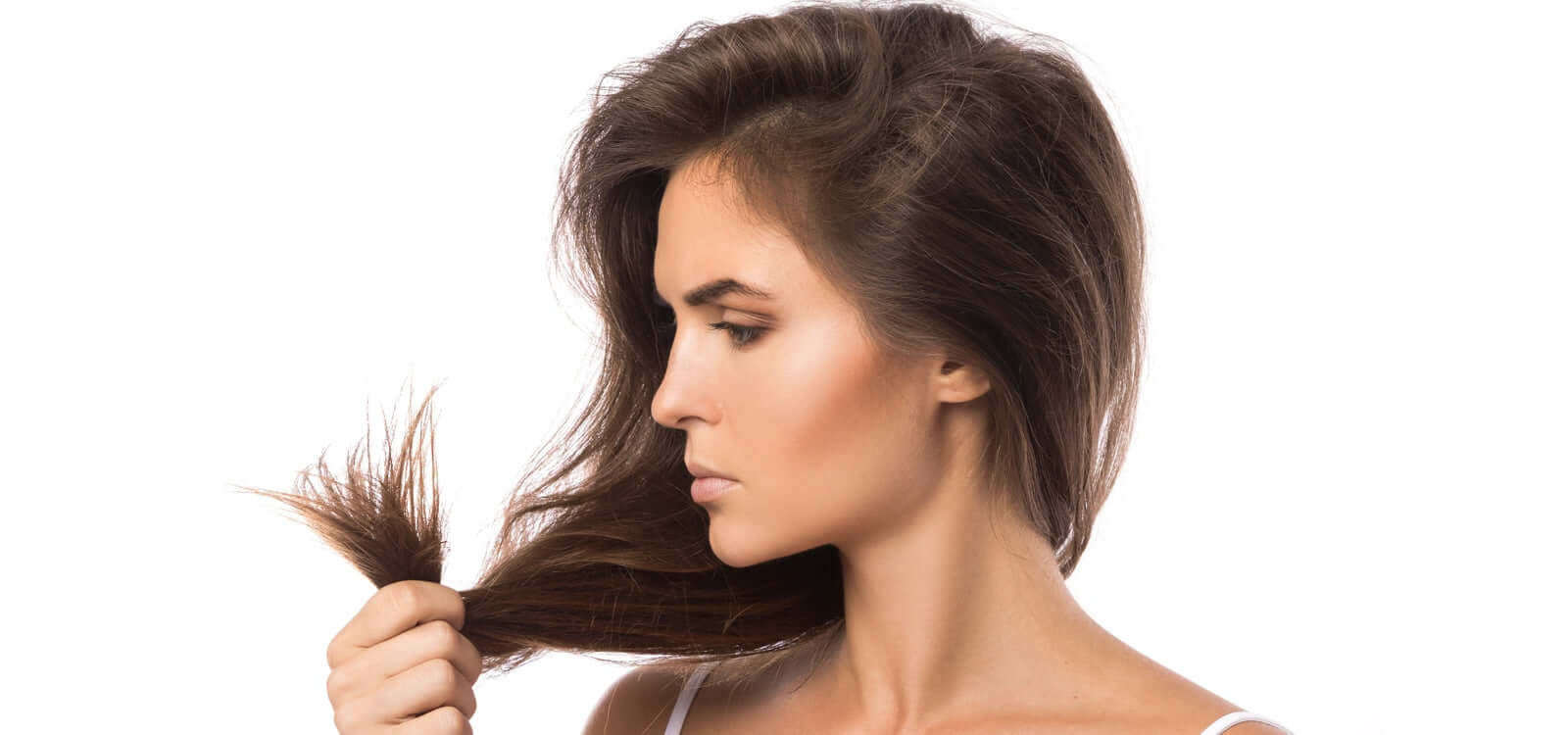 Woman with brown hair holding and looking at her ends