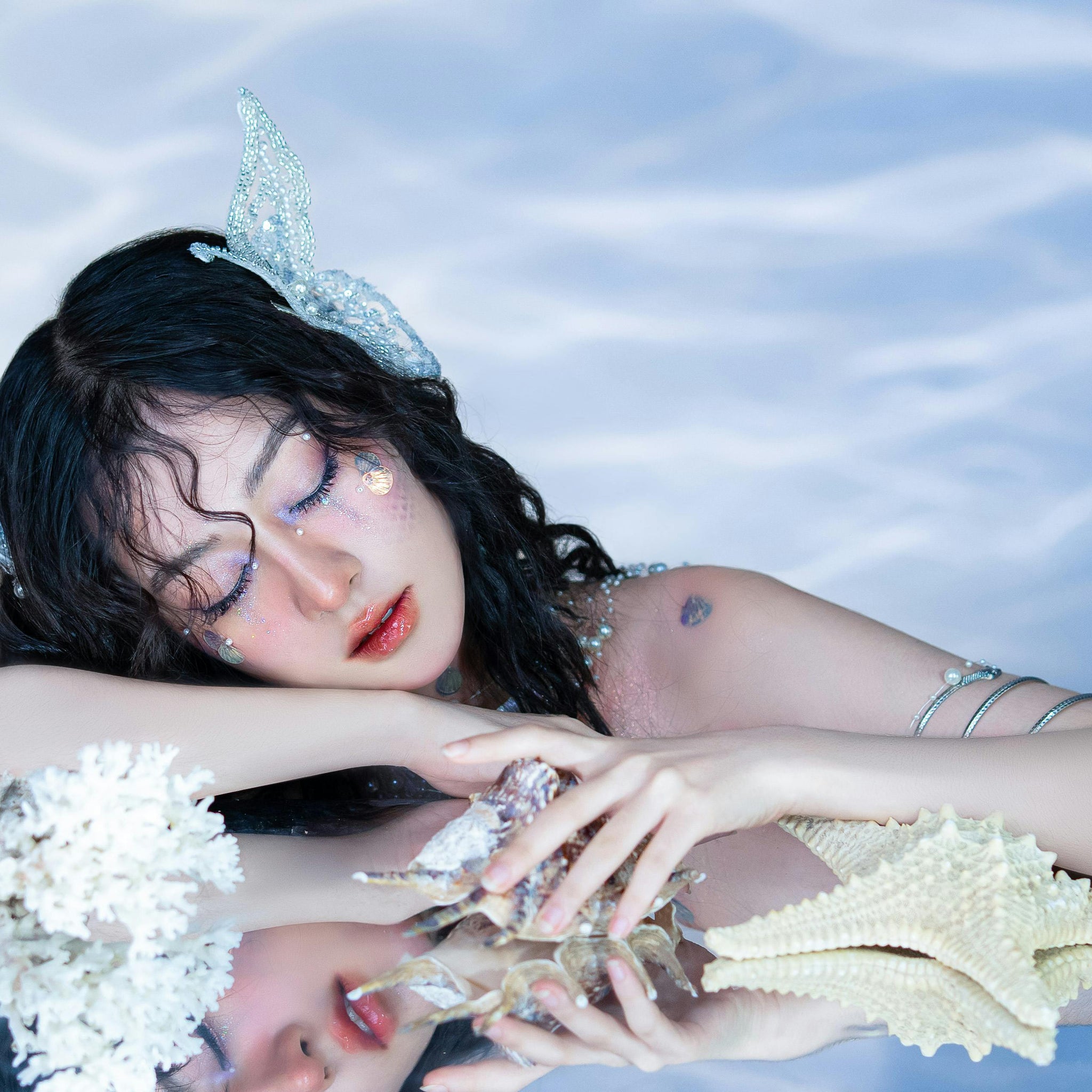 A young woman dressed as a mermaid, surrounded by marine decorations.