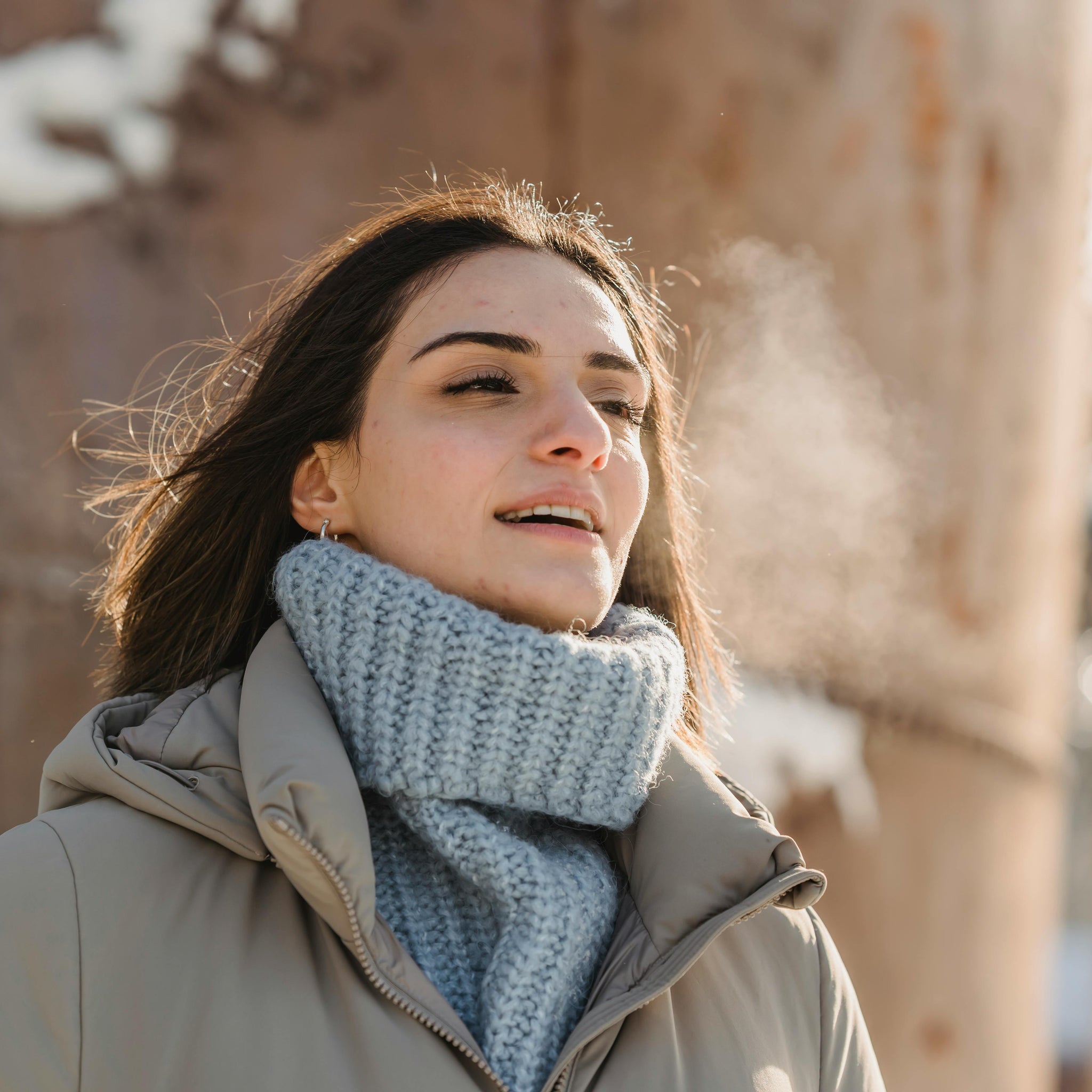 A woman in a knitted jumper and coat walking outside during winter.