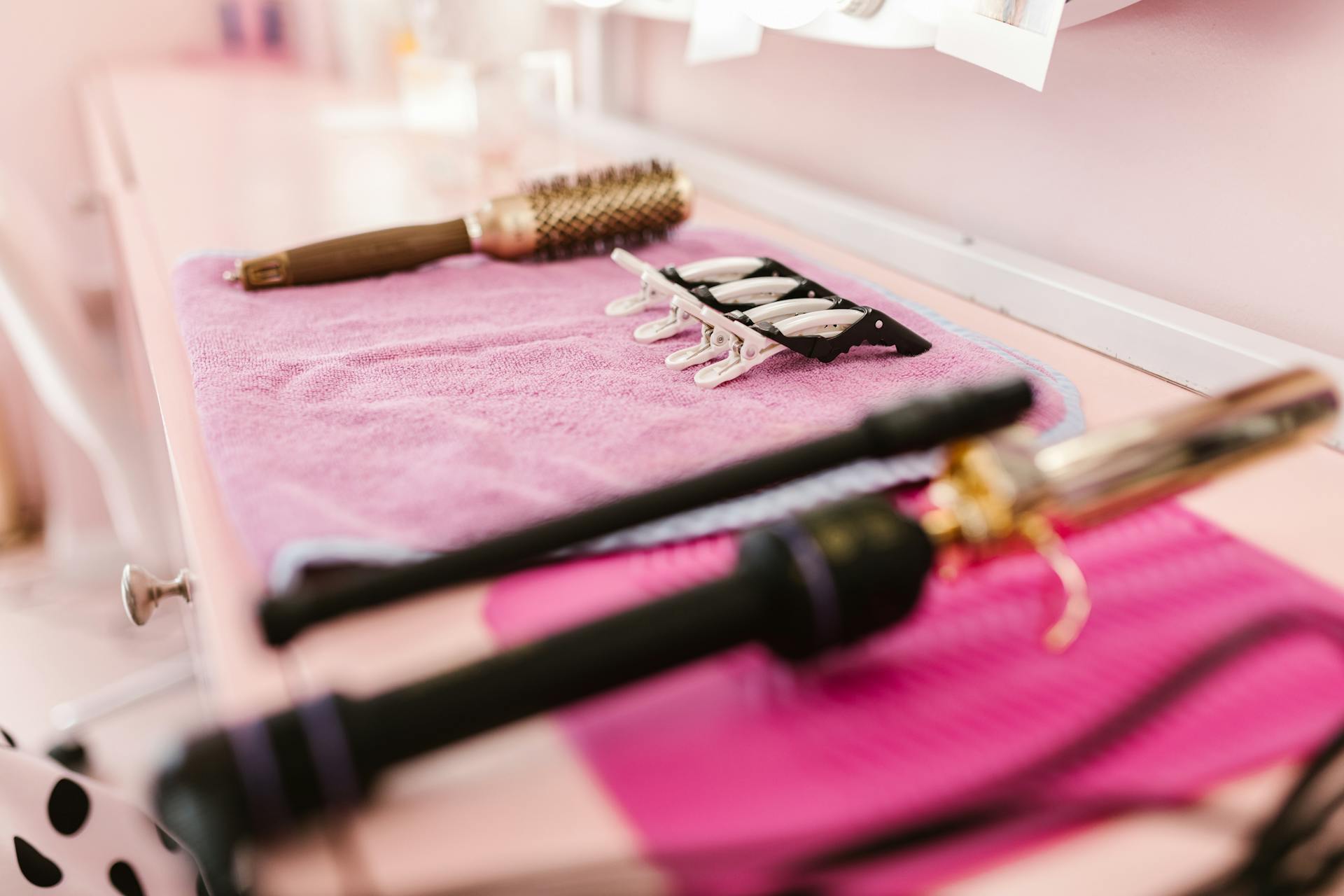 A flat of hair styling tools on a pink towel.