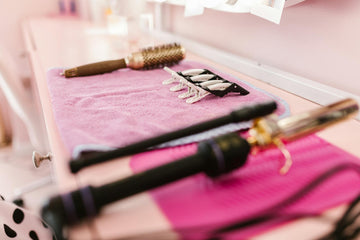 A flat of hair styling tools on a pink towel.