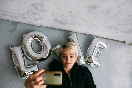 A blonde woman who is growing out a pixie taking a selfie.