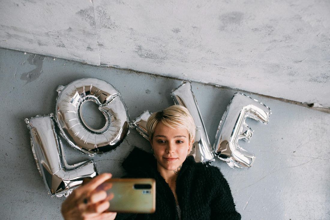 A blonde woman who is growing out a pixie taking a selfie.