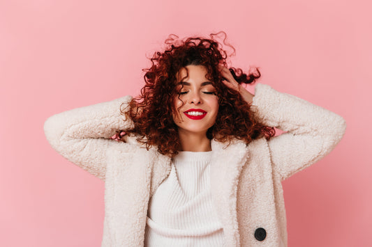 Image of a girl smiling and touching her curly hair.