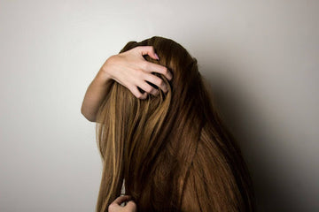 A woman with long brown hair running her hands. Source: Pexels
