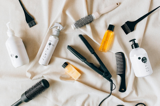 Image of a flat iron tool with lots of hair products. Taken from Pexels