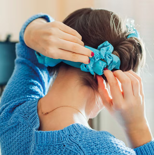Image of a girl tying her hair up with a satin heatless curler. 