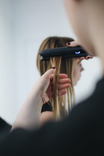 Image of a girl with blonde hair getting her hair straightened.