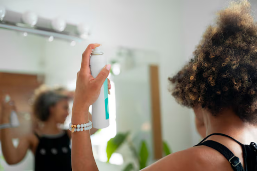 Image of a woman spraying her hair with a mist.