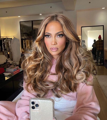 Image of JLo with big bouncy voluminous hair, posing in the mirror. Taken from Instagram/Glamour