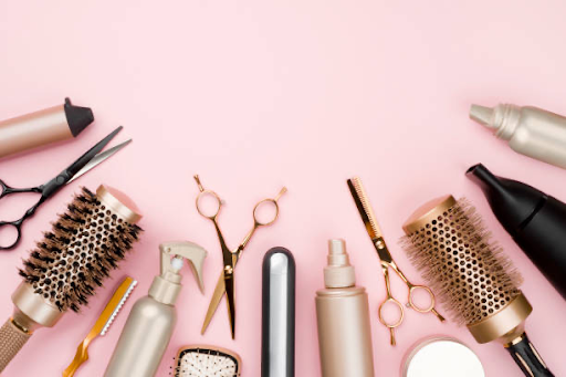 Image of lots of hair tools on a pink surface. 