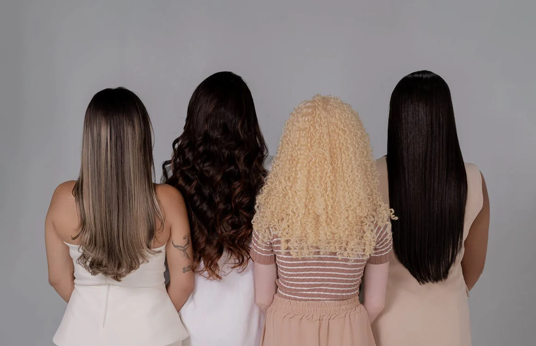 Diverse hairstyles on four women who are facing a wall