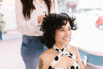 A smiling woman with healthy, shiny hair sitting in a salon chair.