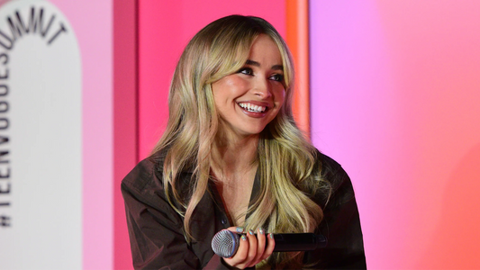 A smiling Sabrina Carpenter with fluffy bangs.