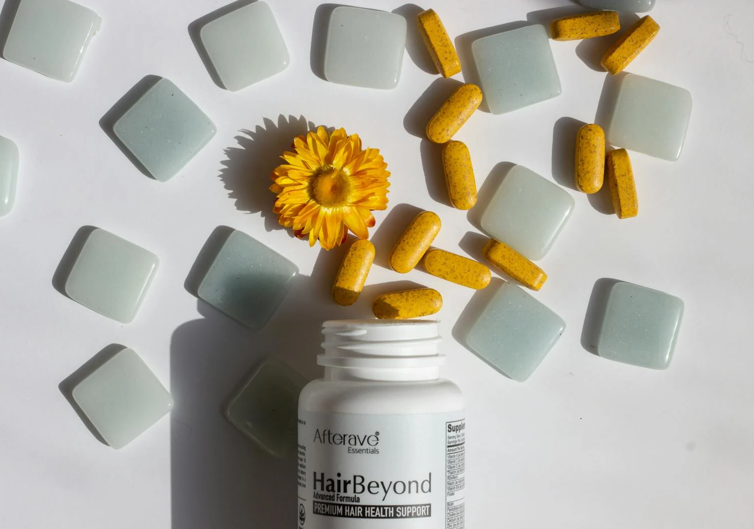 A bottle of supplements spilled out on a white surface.