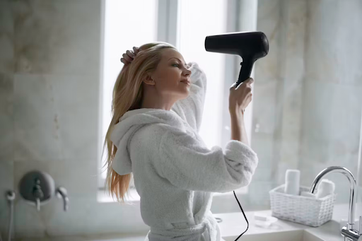 Image of a girl blowdrying her hair.