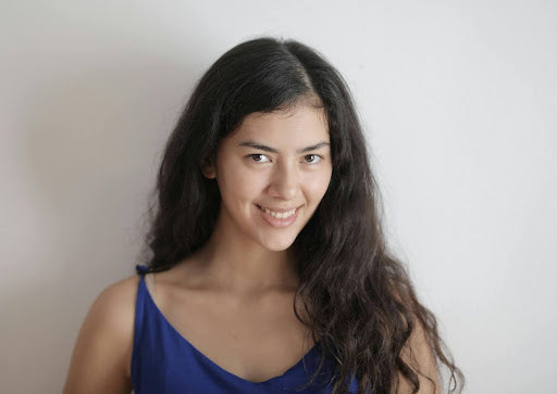 Dark-haired woman with air-dried 2B hair, looking at the camera, against a white backdrop.