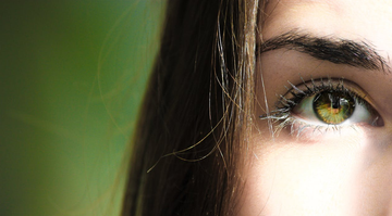 A close-up of a young, brunette woman with fine hair and green eyes.