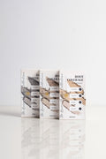 Three boxes of Lauren Ashtyn root coverage powder leaning upright side-by-side in shades of black, dark brown, and light brown.