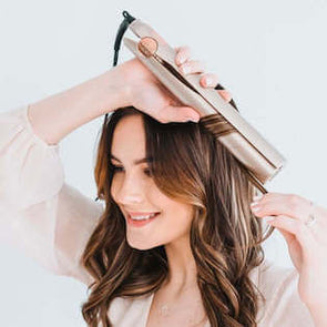 Brunette woman using the TYME Iron for loose curls.