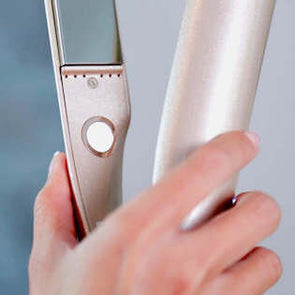 Woman holding TYME Iron showing the power button with set it and forget feature.